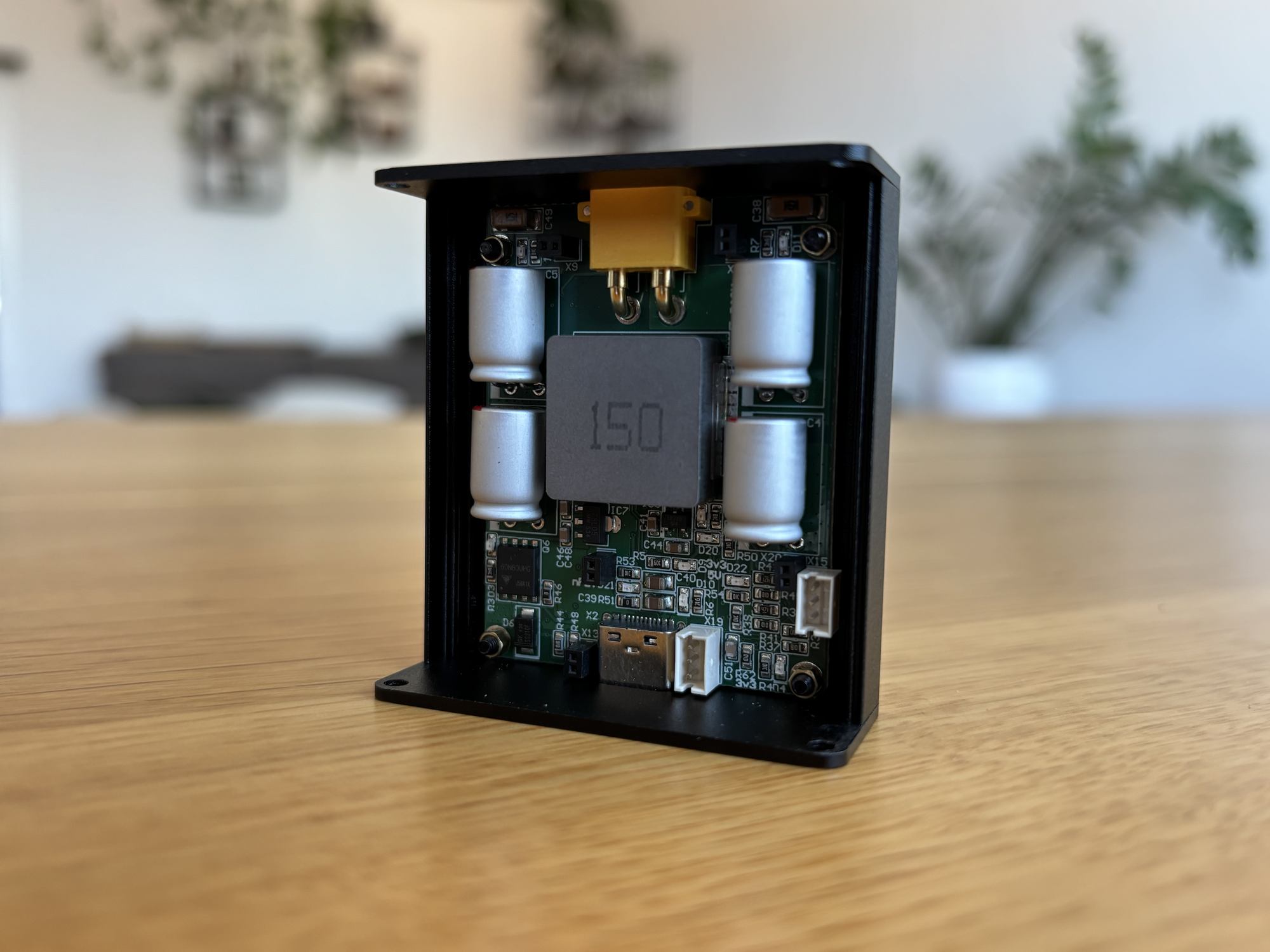 Compact USB-C battery charger adapter board in a small black enclosure, next to its output connector