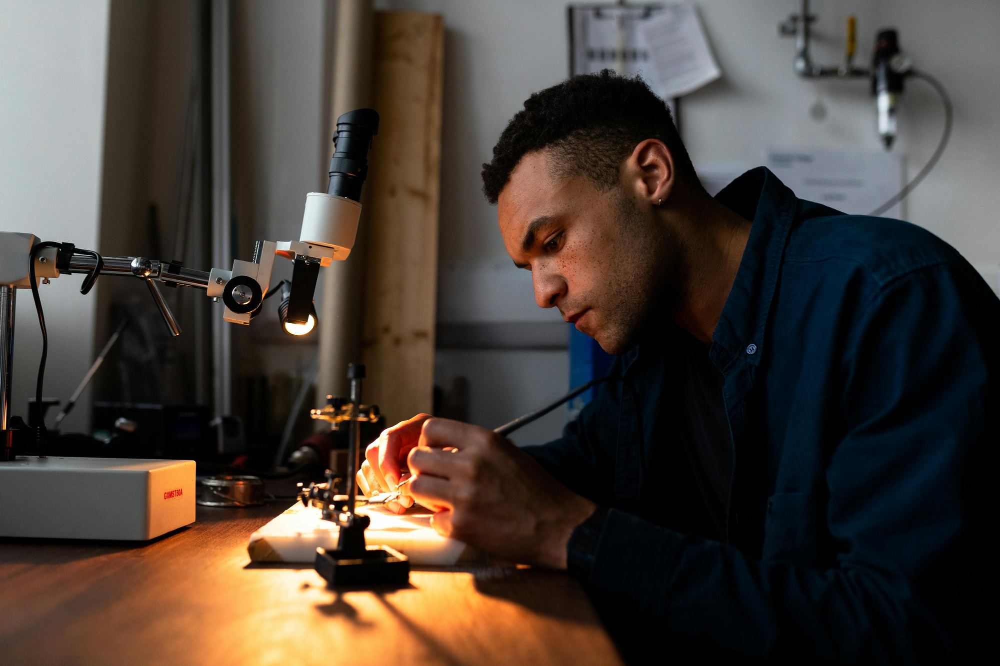 Engineer assembling a custom power electronics prototype under a bench microscope